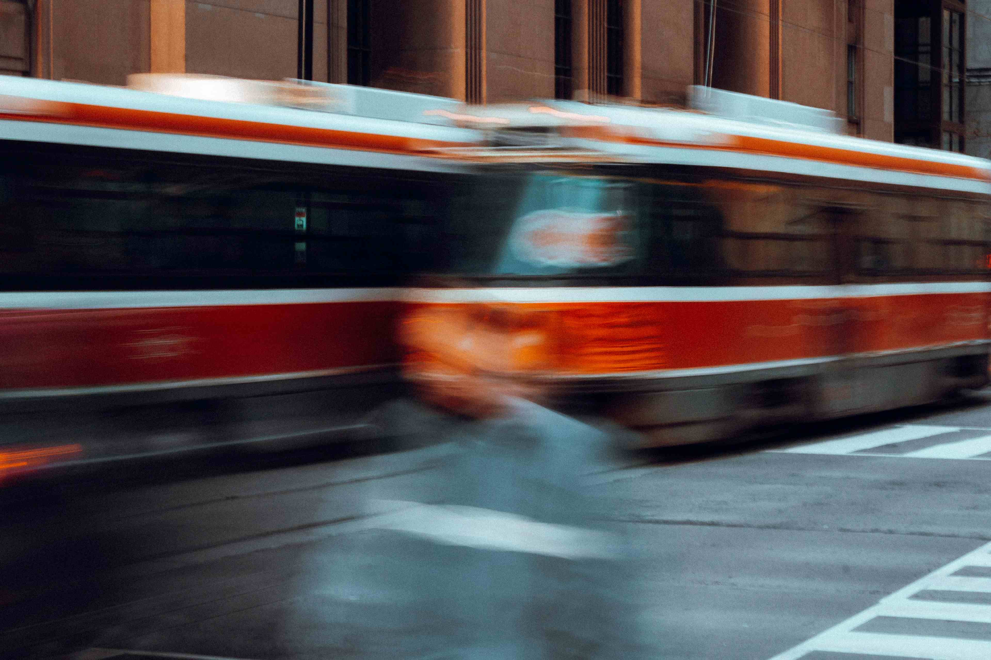 A long exposure of a man crossing the road in Toronto's financial district with two transit streetcars passing in the background